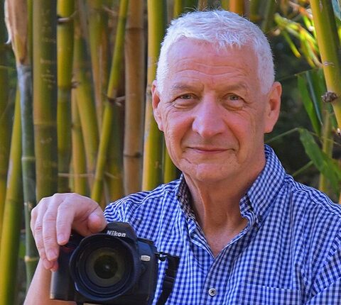 white haired man holding digital camera